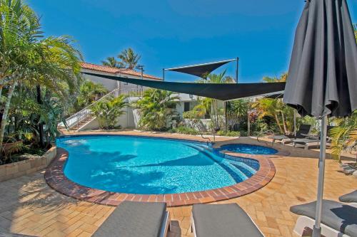 a swimming pool with an umbrella and chairs at Sandcastles On Currumbin Beachfront, Gold Coast in Gold Coast