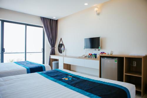 ein Hotelzimmer mit 2 Betten und einem TV in der Unterkunft COCOSEA HOTEL in Ðiệp Sơn