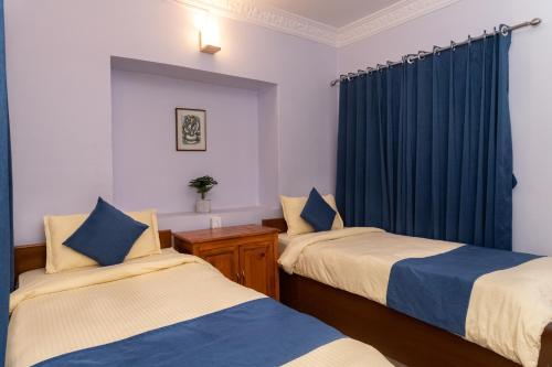 a bedroom with two beds and a blue curtain at Gaurishankar Backpackers hostel in Pokhara