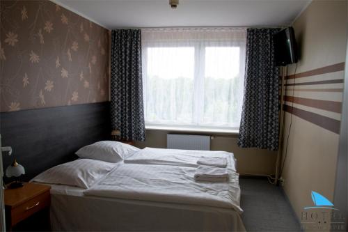 een bed in een slaapkamer met een groot raam bij Na Skarpie in Olsztyn