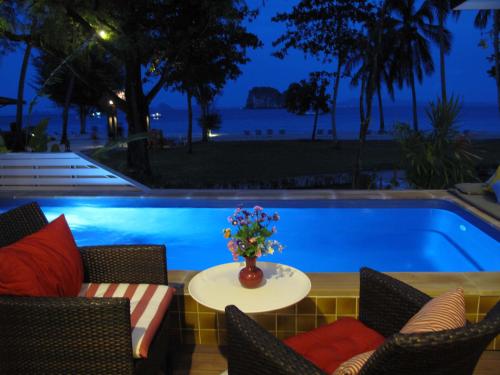 a pool with chairs and a table with a vase of flowers at Koh Hai Fantasy Resort & Spa in Ko Ngai