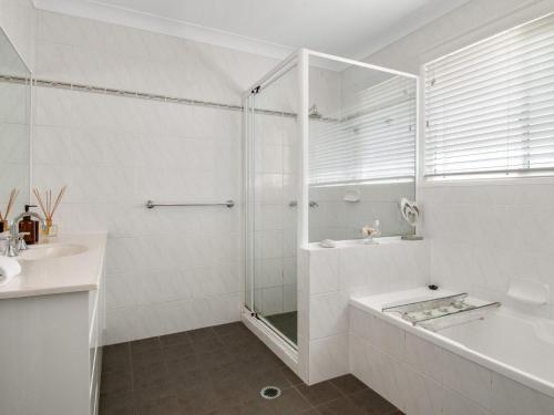 a bathroom with a shower and a tub and a sink at Ardem at Byron in Byron Bay