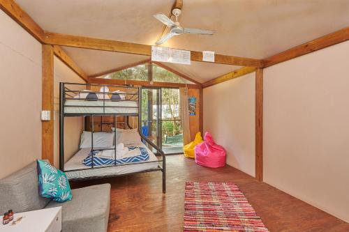 a room with two bunk beds and a ceiling fan at Arts Factory Lodge in Byron Bay