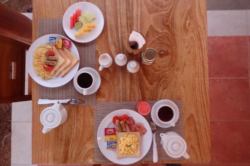 een tafel met borden eten en kopjes koffie bij HoneyBee Huts in Nusa Lembongan