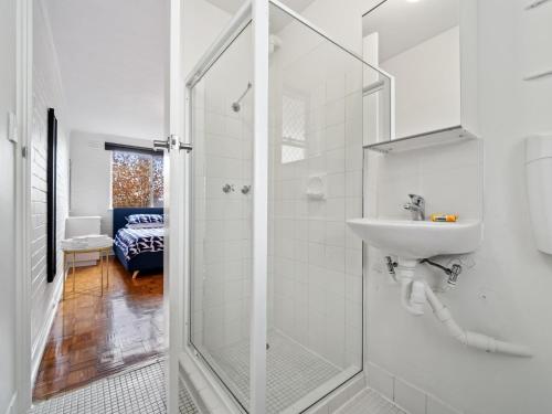 a white bathroom with a shower and a sink at Pronto Apartments in Perth