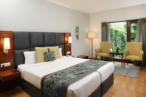 a hotel room with a large bed and two chairs at Ahuja Residency Sunder Nagar in New Delhi