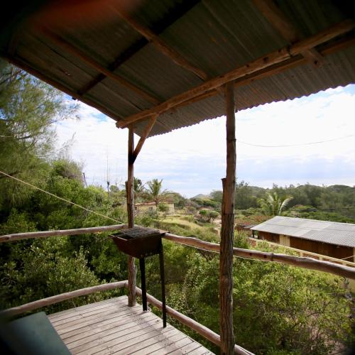 a wooden porch with a view of the forest at Tree House Cottage, Ocean View in Praia do Tofo