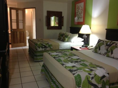 a hotel room with two beds and green walls at Hotel Normandie Limited in Port-of-Spain