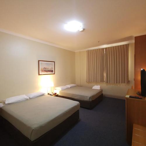 a hotel room with two beds and a television at Criterion Hotel Perth in Perth