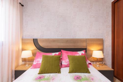 ラ・レスティンガにあるHome2Book Charming Apartment & Diving La Restingaのベッドルーム1室(ピンクと緑の枕が付いたベッド1台付)