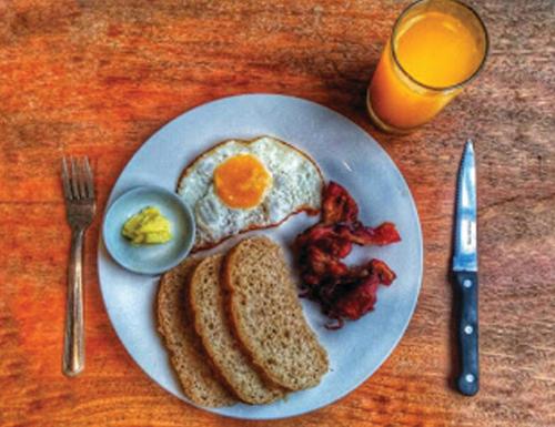 a plate of breakfast food with eggs bacon and toast at Seaslugs Travellers Inn in El Nido
