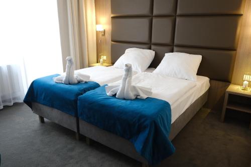 two swans on a bed in a hotel room at Hotel Delicjusz in Trzebaw