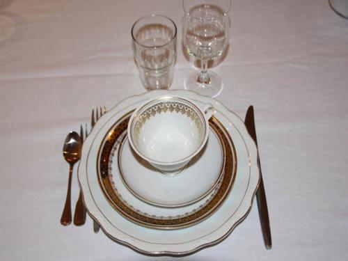 einen Tisch mit einem Teller, einer Schüssel, einer Gabel und einem Messer in der Unterkunft "Schwarzer Speicher" Stralsund in Stralsund