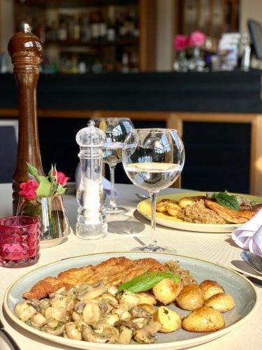 a table with two plates of food and a glass of wine at Hotel Delicjusz in Trzebaw