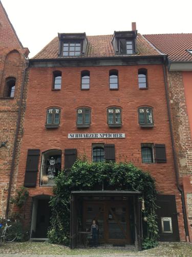 a red brick building with a woman sitting in a window at "Schwarzer Speicher" Stralsund in Stralsund