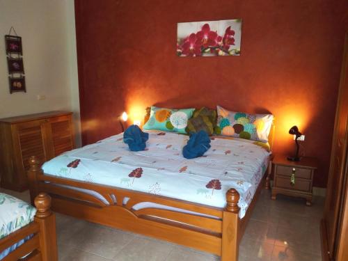 a bedroom with a wooden bed with blue bows on it at Nananuira Apartment and Room in Khao Lak