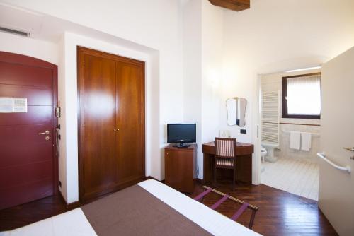 a bedroom with a bed and a desk with a television at Alla Rocca Hotel Conference & Restaurant in Bazzano