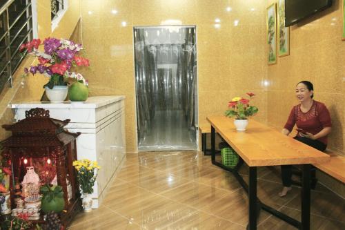 a woman sitting at a table in a room with flowers at Saigon City Center Hostel in Ho Chi Minh City
