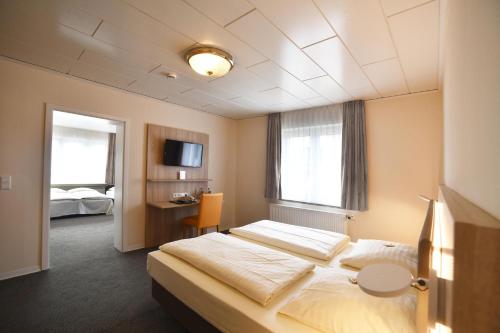 a hotel room with two beds and a television at Römerhof in Stuttgart