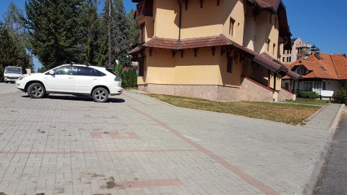 Un coche blanco aparcado delante de un edificio en Apartman Adzic, en Zlatibor