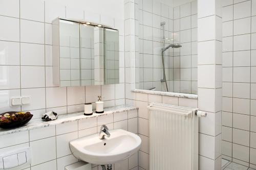 W białej łazience znajduje się umywalka i lustro. w obiekcie Das Alte Kino in Barth - Die Ferienwohnung w mieście Barth