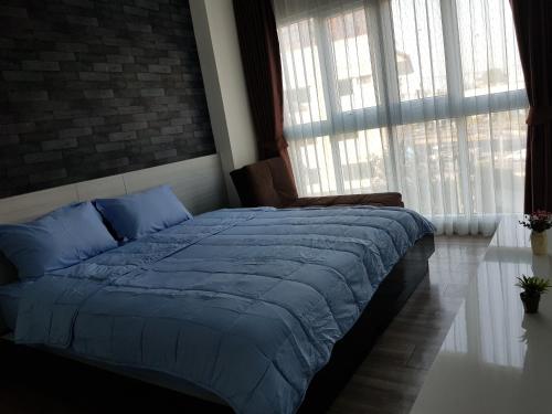 a bedroom with a bed with blue sheets and windows at The Prio Signature Condo Chiangmai in Chiang Mai