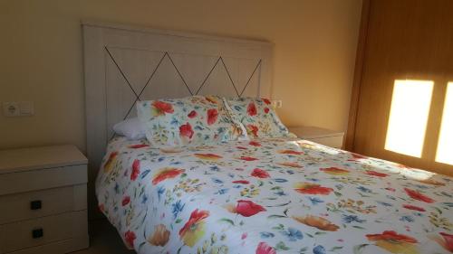 a bedroom with a bed with a floral bedspread at El hogar de Frida in Ourense