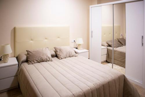 um quarto branco com uma cama grande e um espelho em APARTAMENTOS COSTA XUÑO em Porto do Son