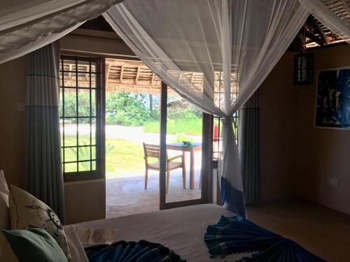 a bedroom with a bed and a view of a patio at Driftwood Beach Lodge in Jambiani