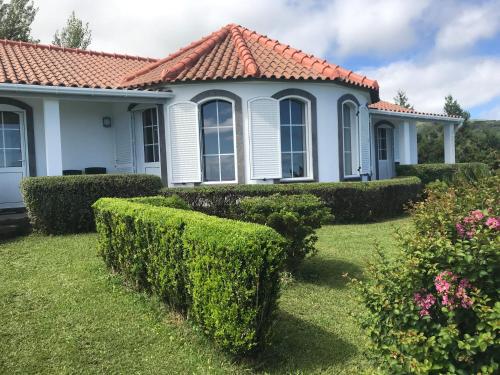 ein weißes Haus mit rotem Dach und Büschen in der Unterkunft Villa Ferreirinha in Santa Cruz das Flores