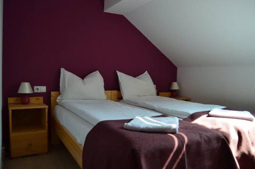 1 Schlafzimmer mit 2 Betten und einer lila Wand in der Unterkunft Csengettyűs in Siculeni