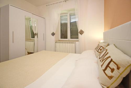 a white bedroom with a large bed and two windows at Apartment Plese in Baška