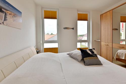 グロヴェにあるFerienwohnung Sonneneckのベッドルーム1室(白いベッド1台、窓2つ付)