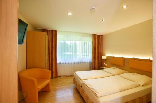 a bedroom with a bed and a chair and a window at Kulinarium an der Glems in Stuttgart