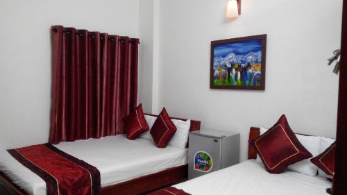 2 camas individuales en una habitación con cortinas rojas en Kara Beachside Guesthouse, en Da Nang