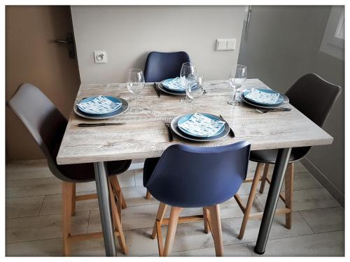 a wooden table with chairs and plates and wine glasses at -CAPCIR- Standing, cosy, 50m de la plage, parking, wifi in Canet-en-Roussillon