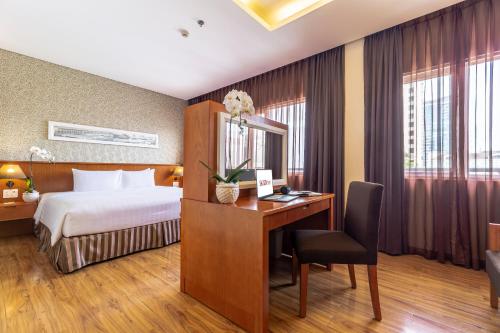 a hotel room with a bed and a desk with a computer at Saigon Hotel Dong Du in Ho Chi Minh City