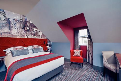 a hotel room with a bed and a red chair at Malmaison Edinburgh City in Edinburgh
