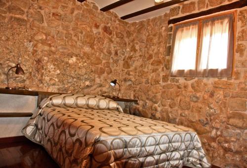 ein Schlafzimmer mit einem Bett in einer Steinmauer in der Unterkunft La Serra Rural in Horta de San Joan