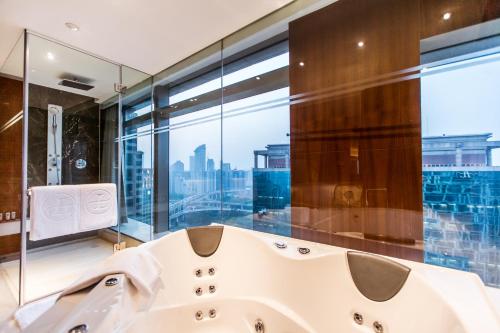 baño con bañera blanca y ventana grande en The Langham, Shanghai, Xintiandi en Shanghái