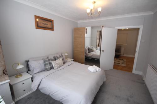 1 dormitorio con cama blanca y espejo en The Uxbridge House en Uxbridge