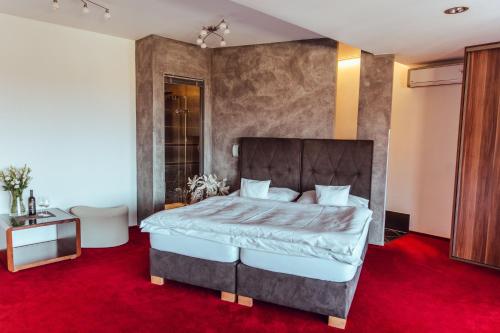 a bedroom with a large bed with a red carpet at Hotel Garni Klaret in Valtice