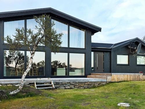 a black house with large windows and a tree at 6 person holiday home in Kvalsund in Repparfjord