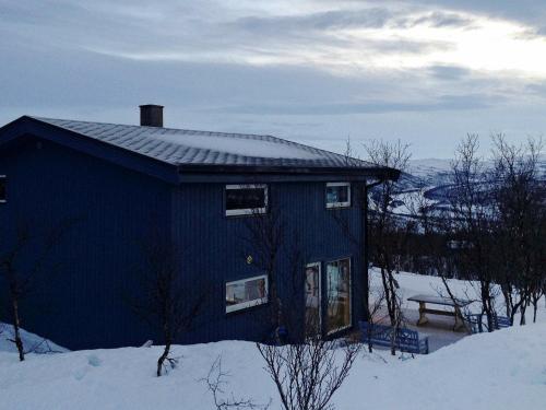 a blue house in the snow with a bench at 6 person holiday home in Kvalsund in Repparfjord