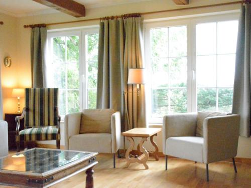 uma sala de estar com 2 cadeiras, uma mesa e janelas em Spacious villa in Daverdisse with large garden em Daverdisse
