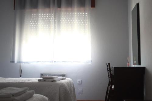 a bedroom with a bed and a window with a curtain at Caçula, Alojamento Local in Torre de Moncorvo