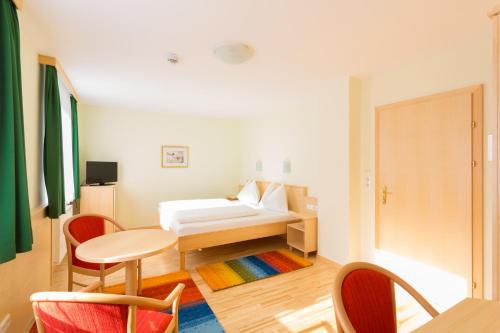um quarto com uma cama, uma mesa e cadeiras em Hotel Kindler 2,0 Self-Check-In em Leoben