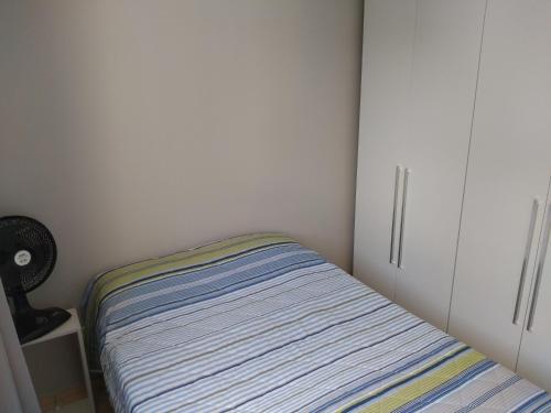 een kleine slaapkamer met een bed en een witte kast bij Residencial in Belo Horizonte