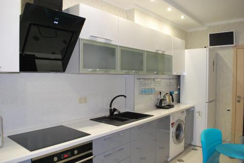 uma cozinha com armários brancos, um lavatório e uma máquina de lavar louça em Apartment on Gvardeyskiy em Rostov on Don