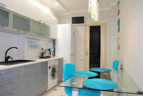 uma cozinha com cadeiras azuis e uma mesa de vidro em Apartment on Gvardeyskiy em Rostov on Don